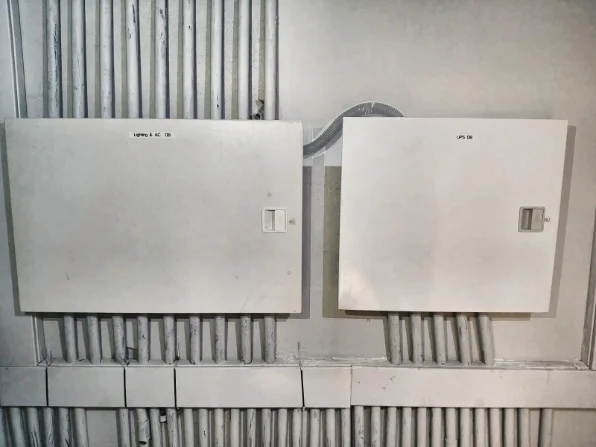 Switchboard enclosures mounted on the wall with conduit runs before final wiring